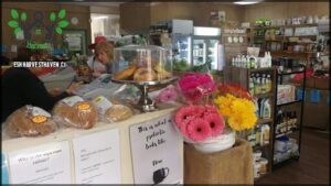 A woman is standing in front of a display of pastries and flowers.