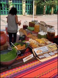 A woman is standing in front of a table filled with food, including a variety of bottles and bowls.