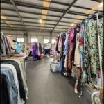 A woman is standing in front of a table full of clothes.