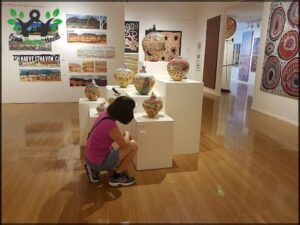 A woman kneeling in front of a display of vases.