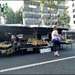 A woman walks past a fruit stand on the street.