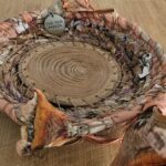 A wooden bowl with a metal tag that reads "find your way" sits on a table.