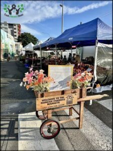 A wooden cart with flowers in it is parked on the side of the road.
