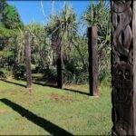 A wooden carving of a face is displayed in a grassy area.