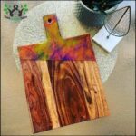 A wooden cutting board with a rainbow pattern on it.