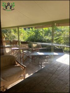 A wooden deck with a table and chairs, overlooking a forest.