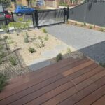 A wooden deck with a view of a fence and a gate.