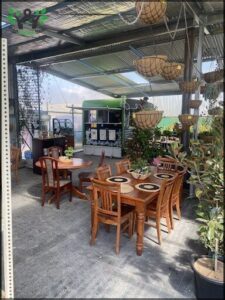 A wooden dining table with chairs is set up in a patio area.