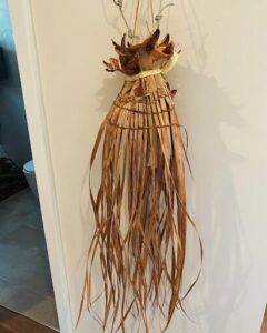 A wooden object with a long tail hangs on a wall.