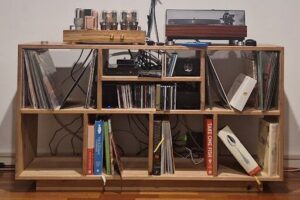 A wooden shelf with a collection of books, records, and other items.
