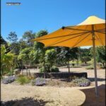 A yellow umbrella is set up in a park, providing shade for visitors.
