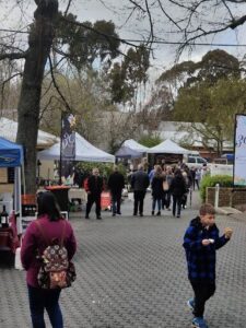 A young boy is eating a hot dog while walking with his mother in a crowded area.