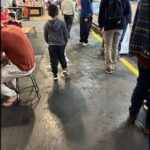 A young boy wearing a grey hoodie walks down a hallway.