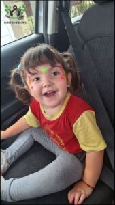 A young girl with a smile on her face and a yellow shirt with a red collar.