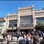 people walking in front of a building with a sign that says mercado san miguel