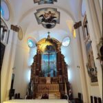 The interior of a church features a large cross and a painting of Jesus.