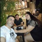 Three friends pose for a photo at a cafe, enjoying their time together.