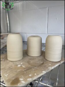 Three white vases are sitting on a table, ready to be used for decoration.