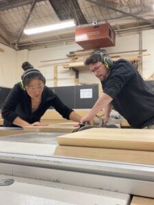 Two people working together on a project, one of them wearing headphones.