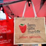 Two red tote bags with the words "Farm Gate Market Hobart, Tasmania" written on them.