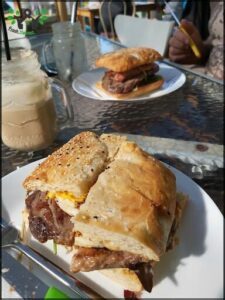 Two sandwiches are on a table, one with meat and the other with meat and cheese.