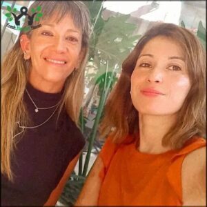 Two women are sitting next to each other, smiling and posing for a picture.