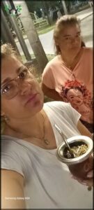 Two women standing next to each other, one holding a bowl of food.