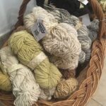 A basket full of yarn, including a variety of colors and textures.