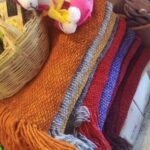 A basket of yarn and a stuffed animal are displayed on a table.