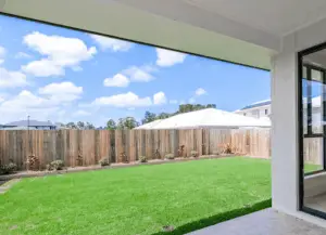 A beautifully manicured lawn with a fence and a house in the background.