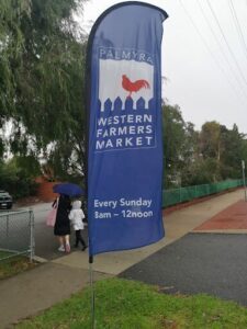 A blue flag with a rooster on it is displayed on a street.