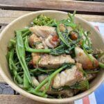 A bowl of food with meat, greens, and rice.