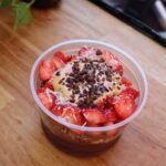 A bowl of strawberries and chocolate topped with whipped cream.