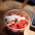 A bowl of strawberries with white powder on top.
