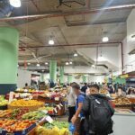 A bustling market scene with people shopping for fresh produce.