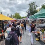A bustling outdoor market filled with people shopping and vendors selling their wares.