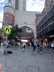 A busy city street with people walking and sitting.