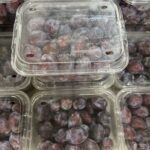 A close-up of a plastic container filled with grapes.