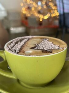 A cup of coffee with a christmas tree on top.