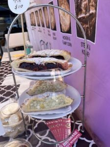 A display of pastries, including a variety of pies and cakes, is presented on a tiered stand.
