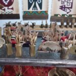 A display of wooden carvings, including a carved wooden spoon, are arranged on a table.