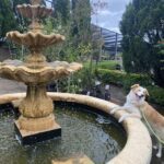 A dog is standing on a fountain, looking at the camera.