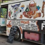 A food truck with a cow painted on the side is parked on the street.