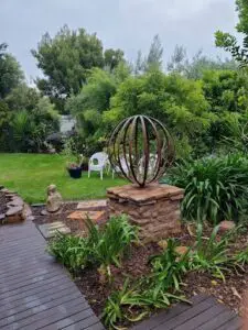 A garden with a stone circle and a metal globe.
