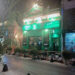 A green and white building with a lit up sign.