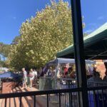 A group of people are gathered around a table, possibly at a market or event.
