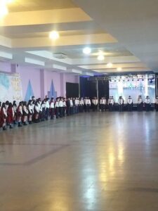 A group of people wearing uniforms are standing in a large room, possibly a gymnasium.