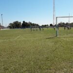 A group of soccer players are on the field, with one player in the goal.