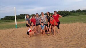 A group of women posing for a photo on a beach.