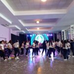 A group of young women are dancing in a room, possibly at a party or event.
